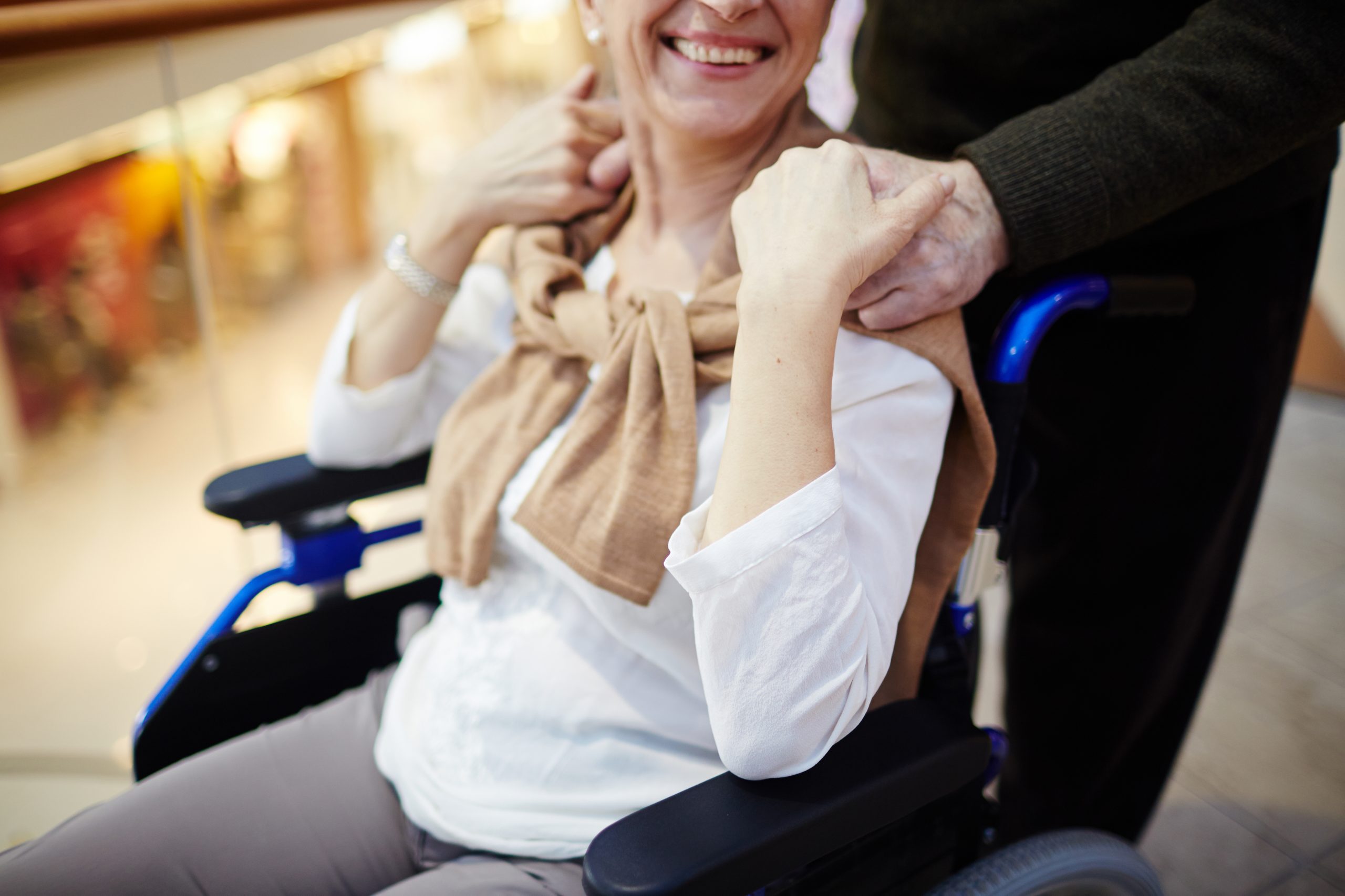 Happy senior female in wheelchair and her husband near by